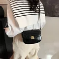 Black crocodile embossed leather saddle bag with gold metal buckle shown on a model - No Pendant / 20x6x14cm / Black