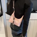 Pink patent leather underarm bag with COIN logo and woven tassel charm shown on model - Pink With Pendant / Pink