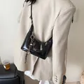 Glossy black hobo shoulder bag with silver hardware on a beige blazer background - Black With Rabbit Pendant / Black