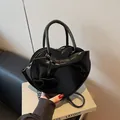 Elegant black heart-shaped handbag in glossy patent leather with a stylish bow decoration - Black
