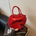 Glossy red heart-shaped handbag with a decorative bow and adjustable crossbody strap - Burgundy