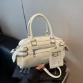 Cremeweiße Boston-Tasche aus Leder mit silbernen Beschlägen und modischem Anhänger - Gebrochenes Weiß