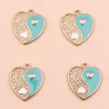 Macro detail of heart-shaped Yin Yang pendants with cyan enamel and hammered gold finish - Blue