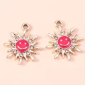 Close-up of alloy sun pendants with pink enamel smiley faces and small rhinestones - Gold Red