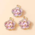Macro detail of three purple enamel flower pendants with gold plating and white crystals - Gold Purple