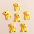 Close-up of yellow resin cartoon bears with pink bowties for DIY phone case crafts - Yellow