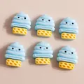 Flat lay of six mini blue resin ice cream charms with cute faces for DIY crafts and decor - Blue