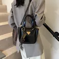 Glänzende schwarze Beuteltasche mit goldenem Logo und Seidentuch auf einer Treppe - Mit Anhänger / Schwarz