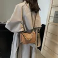 Braune Satteltasche aus Litschileder mit Goldkette und verstellbarem Gurt am Model - Braun