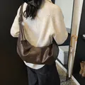 Deep brown soft leather hobo bag with knotted strap shown on a model for daily use - Brown