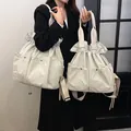 Beige large capacity drawstring tote bag with multi-pocket design shown on model - Off-white / Large