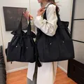 Two sizes of black lightweight nylon drawstring tote bags with silver rivet details - Black / Large