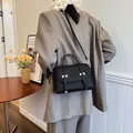 Retro black textured tote bag with top handle and crossbody strap on elegant model - Black
