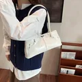 Glossy cream shoulder bag with silver turn-lock and studs shown on a model - 33cmx8cmx14cm / White