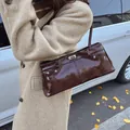 Glossy dark brown vintage shoulder bag with metal lock shown in an autumn outdoor setting - 33cmx8cmx14cm / Brown