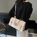 Elegante beige laksleren handtas met zilveren gesp gedragen door een model - Roze