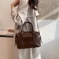 Bolso Boston marrón oscuro en cuero sintético con detalles dorados y asas - Café sin Colgante