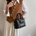 Bolso Boston de cuero negro con herrajes dorados y bolsillo frontal en una modelo - Negro sin Colgante