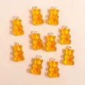 Macro shot of 10 translucent amber resin gummy bear charms with golden loops for DIY jewelry - Orange