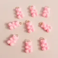 Macro shot of 9 pink resin gummy bear charms with golden rings for DIY jewelry projects - Pink
