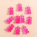 Flat lay of translucent pink resin bear charms with gold loops for DIY jewelry making - Rose Red