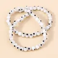 Detailed close-up of three white resin evil eye bead bracelets with black dot motifs - White