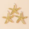 Detail of three resin starfish charms filled with gold leaf and silver link rings - Gold