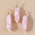 Detail van drie roze zeshoekige kristallen hangers met gouden draadwikkeling - Ijsroze