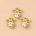 Three gold bow pendants with pearl and rhinestone accents on a beige background - Diamond Flower