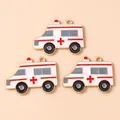 Three enamel ambulance charms with red cross for DIY jewelry making on soft orange background - Pink