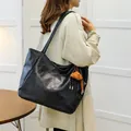 Black leather tote bag with TonTon embossing and bear charm shown on shoulder - With Pendant / Black