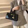 Polished black leather tote bag with elegant gold hardware and sturdy top handles - Black