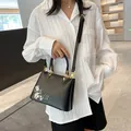 Black leather tote with floral embroidery and gold metal V-shaped accents - Black