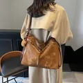Vintage caramel brown large tote bag with bear charm shown in a chic shoulder carry view - Brown with Pendant