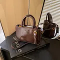 Borsa a mano in pelle color caffè con dettagli dorati e tracolla su libro d'arte - Stile di base / Marrone