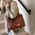 Grande borsa tote marrone retrò con tracolla intrecciata mostrata in un ambiente reale - Stile di base / Marrone