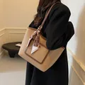 Beige kiezellederen shopper met bruine bies en zijden sjaal in een lifestyle setting - Khaki