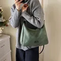 Dark green faux suede tote bag with slim black straps and fashion label in daily setting - Green