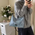 Light blue faux suede hobo bag with chain strap and Fashion label on a model - Blue