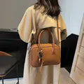 Bruine leren bowlingtas met dubbele handvatten en kwastjes op een beige trenchcoat - 29cmx13cmx20cm / Bruin met Hanger