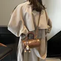Brown leather cylinder crossbody bag with plush monster charm and adjustable strap - With Charm / Brown