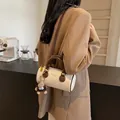 Retro cream cylinder crossbody bag with brown trim and plush monkey charm on a model - With Charm / Off-white