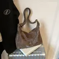Brown vintage leather hobo bag with marble texture displayed on a silver suitcase - Brown