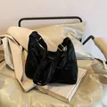 Minimalist black hobo shoulder bag with textured fabric and golden hardware - Black