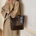 Retro donkerbruine leren tote bag met decoratieve riemen en gouden details op model - koffiekleur