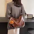 Dunkelbraune PU-Leder Schultertasche in Halbmondform mit Teddybär-Anhänger und Band - Braun
