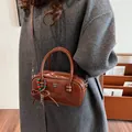 Vintage brown patent leather handbag with bow charm and shoulder strap on grey coat - Brown with Pendant