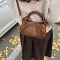 Dark brown pleated dumpling bag with knot detail shown in a stylish outdoor autumn setting - 22*7*13 / Khaki