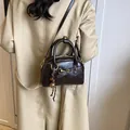 Retro deep brown leather satchel with golden hardware and adjustable strap on a trench coat - With Pendant / Brown