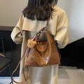 Vintage brown leather tote bag with plush bear charm shown on model's shoulder - Brown with Pendant